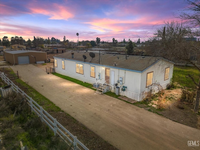 manufactured / mobile home featuring driveway, entry steps, a garage, fence, and an outdoor structure