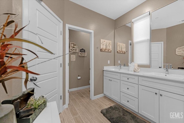 full bath featuring a sink, wood finish floors, toilet, and double vanity