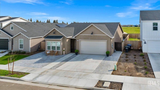 view of front of house with a shingled roof, fence, concrete driveway, roof mounted solar panels, and an attached garage