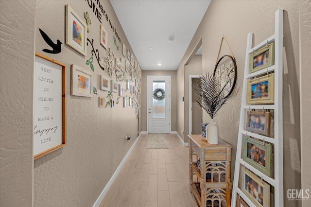 interior space featuring a textured wall, baseboards, and wood finished floors