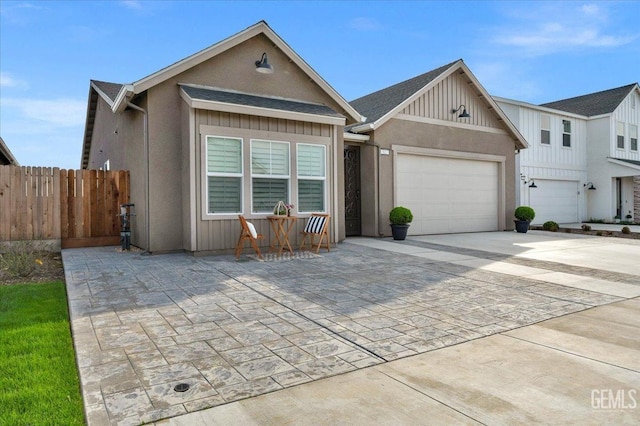 view of front of house featuring an attached garage, board and batten siding, driveway, and fence