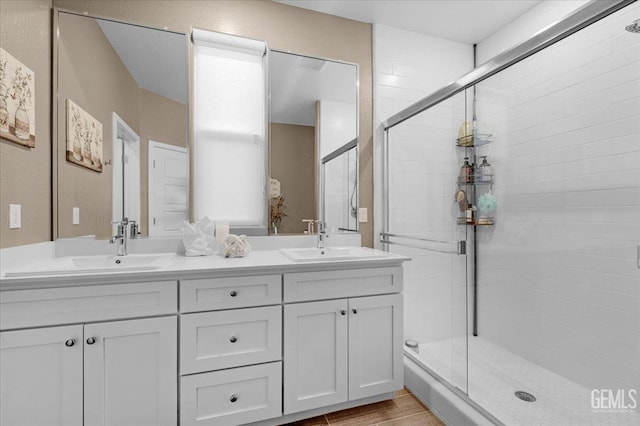 bathroom with a sink, a stall shower, and double vanity