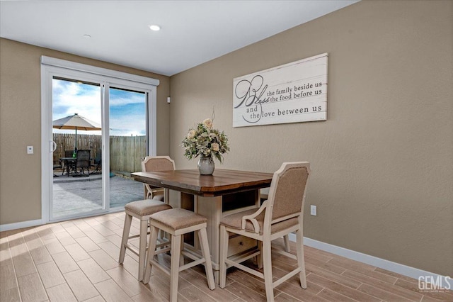 dining room featuring a textured wall, baseboards, and wood finish floors