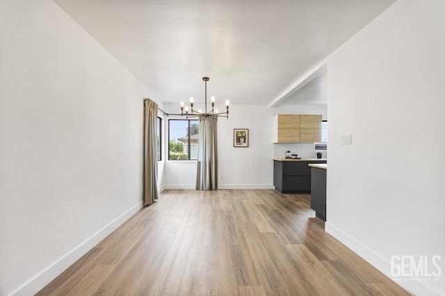 unfurnished dining area with light wood-type flooring, baseboards, and a notable chandelier