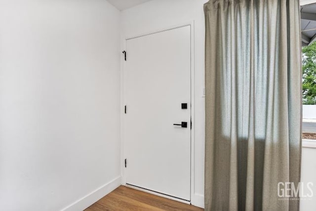 doorway with wood finished floors and baseboards