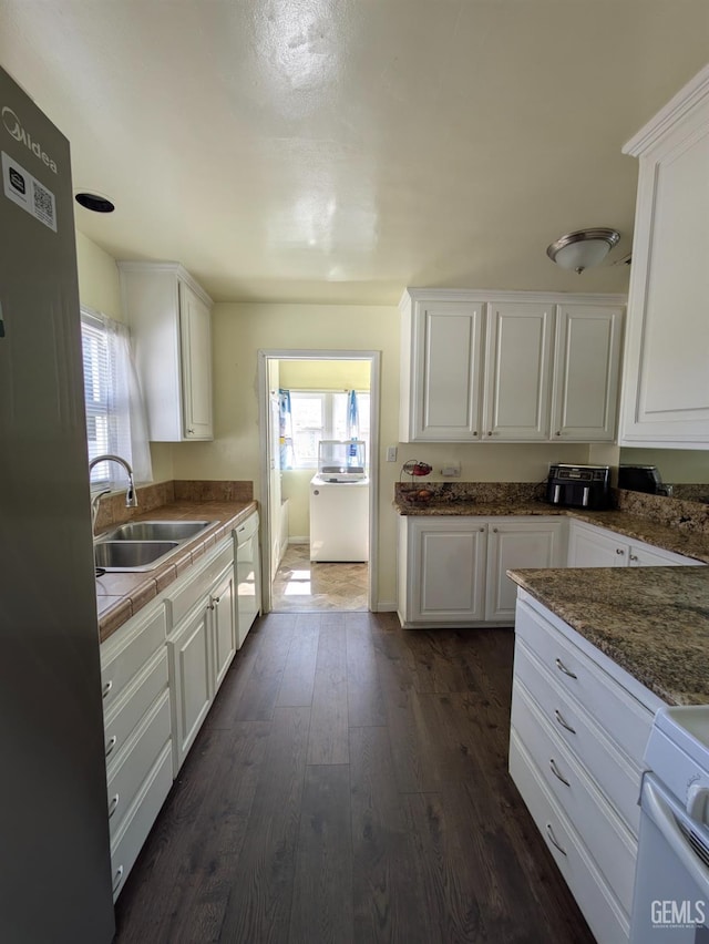 kitchen featuring dark wood-type flooring, a sink, plenty of natural light, white cabinetry, and white appliances