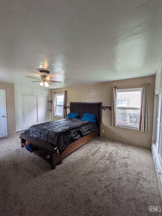 unfurnished bedroom featuring visible vents, multiple windows, a textured ceiling, and carpet floors