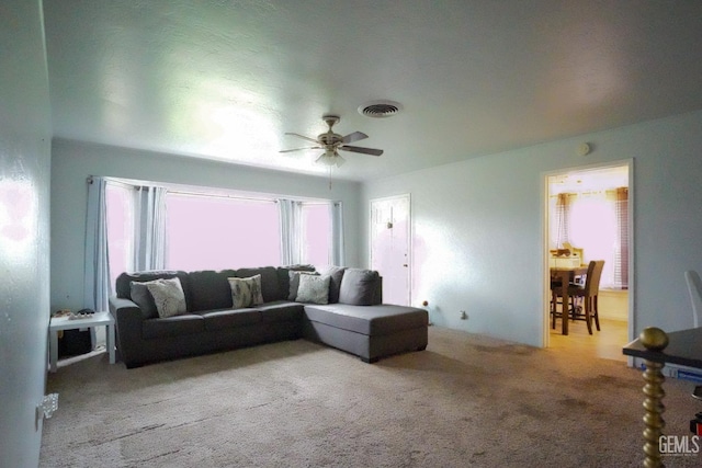 living area with carpet, visible vents, and ceiling fan