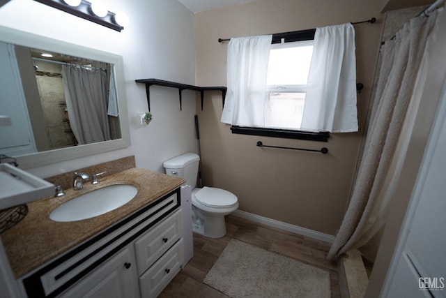 bathroom featuring a shower with curtain, toilet, wood finished floors, baseboards, and vanity