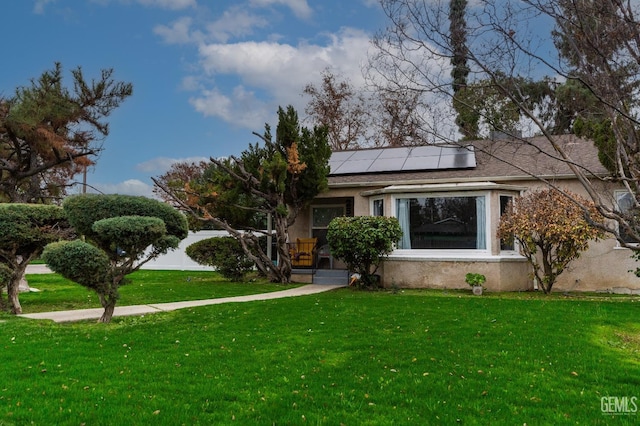 view of front of house featuring stucco siding, solar panels, and a front yard