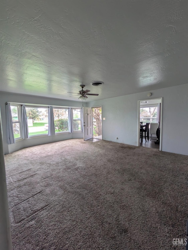 unfurnished living room with plenty of natural light, carpet, and visible vents