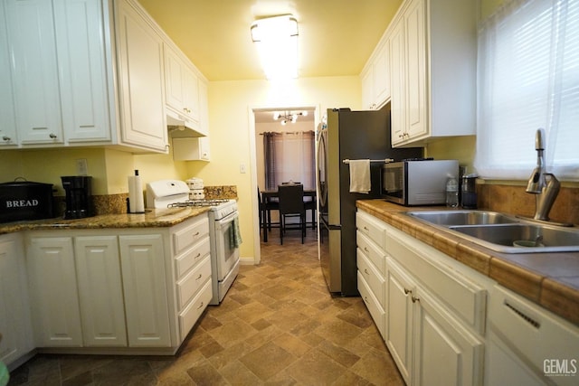 kitchen with under cabinet range hood, white appliances, white cabinets, and a sink