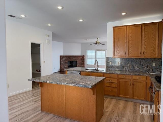 11615 Marazion Hill Ct, Bakersfield, CA 93311 - kitchen featuring a sink, light wood finished floors, a glass covered fireplace, backsplash, and recessed lighting
