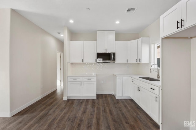3409 Lotus Ln, Bakersfield, CA 93307 - kitchen featuring stainless steel microwave, dark wood-type flooring, decorative backsplash, white cabinets, and recessed lighting