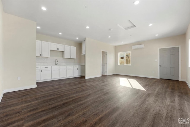3409 Lotus Ln, Bakersfield, CA 93307 - unfurnished living room with attic access, dark wood-style floors, recessed lighting, and an AC wall unit