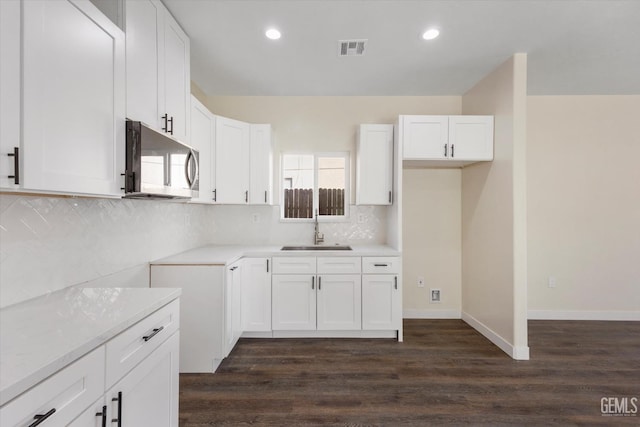 3409 Lotus Ln, Bakersfield, CA 93307 - kitchen featuring stainless steel microwave, dark wood-type flooring, recessed lighting, tasteful backsplash, and white cabinets