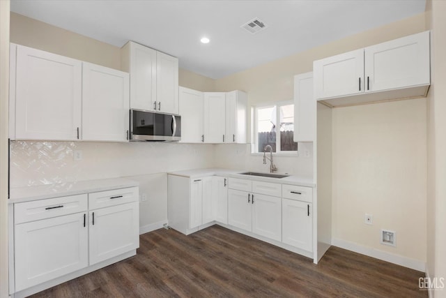 3409 Lotus Ln, Bakersfield, CA 93307 - kitchen featuring stainless steel microwave, dark wood finished floors, backsplash, recessed lighting, and white cabinetry