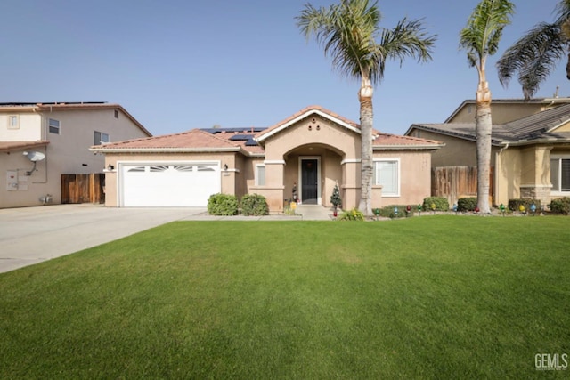 mediterranean / spanish-style house featuring a garage, a front yard, and solar panels