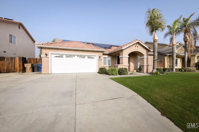 mediterranean / spanish house with solar panels, a garage, and a front yard