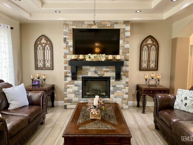 1904 Raymond A Spruance Ct, Bakersfield, CA 93304 - living room with a tray ceiling, wood tiled floors, a stone fireplace, recessed lighting, and arched walkways