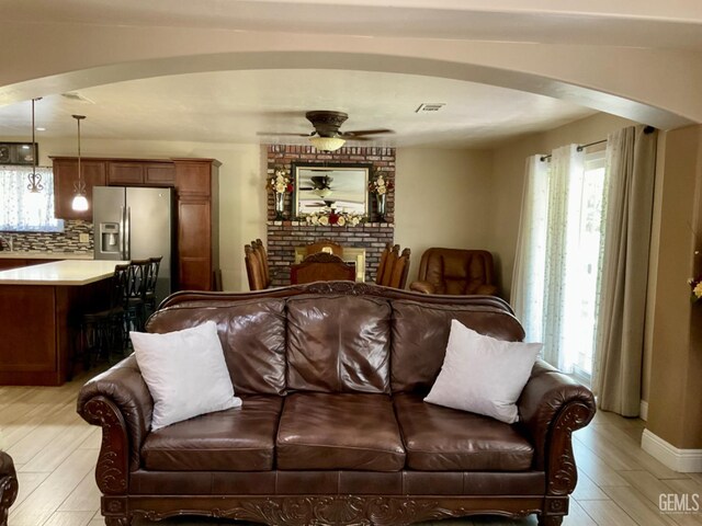 1904 Raymond A Spruance Ct, Bakersfield, CA 93304 - living area featuring arched walkways, ceiling fan, light wood-style floors, and a brick fireplace