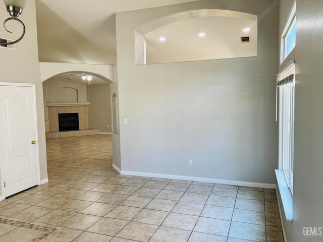 3614 White Sands Dr, Bakersfield, CA 93313 - empty room featuring light tile patterned flooring, a towering ceiling, baseboards, a tile fireplace, and arched walkways