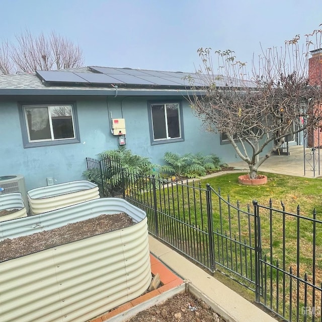 view of side of property featuring a lawn, solar panels, and central AC