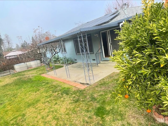 back of house with a lawn, solar panels, and a patio