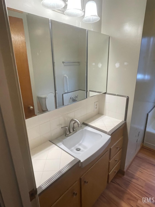 bathroom with toilet, hardwood / wood-style floors, backsplash, and vanity