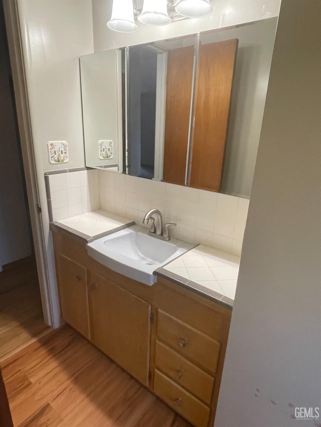 bathroom featuring wood-type flooring, vanity, and tasteful backsplash