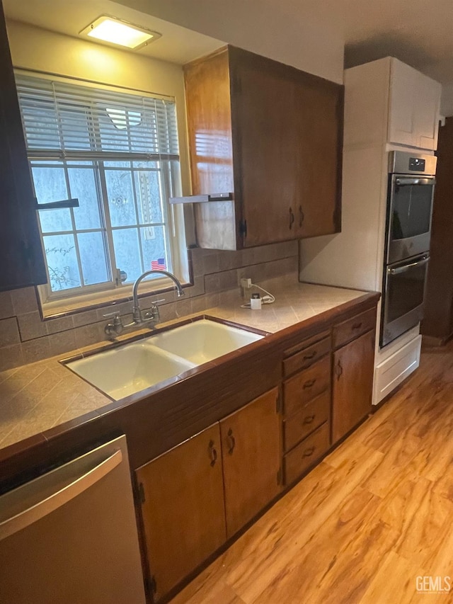 kitchen with a wealth of natural light, appliances with stainless steel finishes, sink, and tile countertops