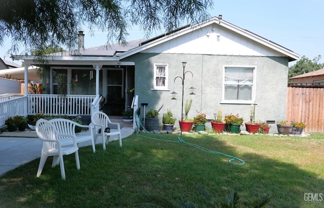 rear view of property with solar panels and a yard