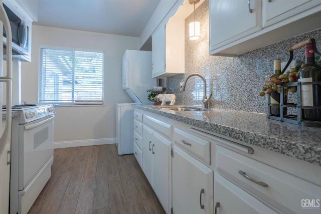 kitchen featuring white appliances, wood finished floors, a sink, white cabinetry, and decorative backsplash