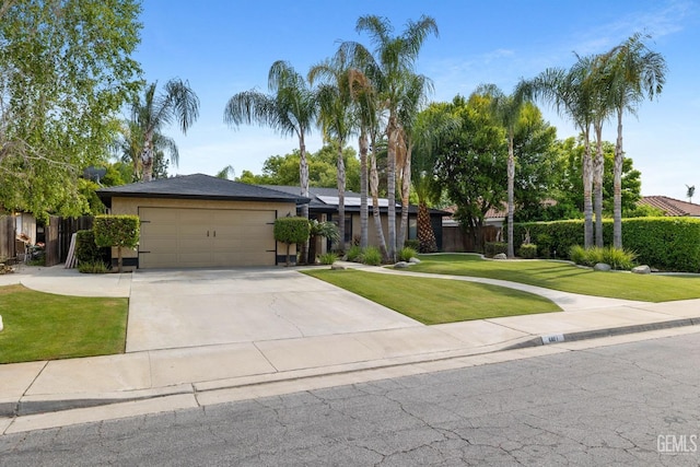 view of front of home with concrete driveway, an attached garage, fence, and a front yard