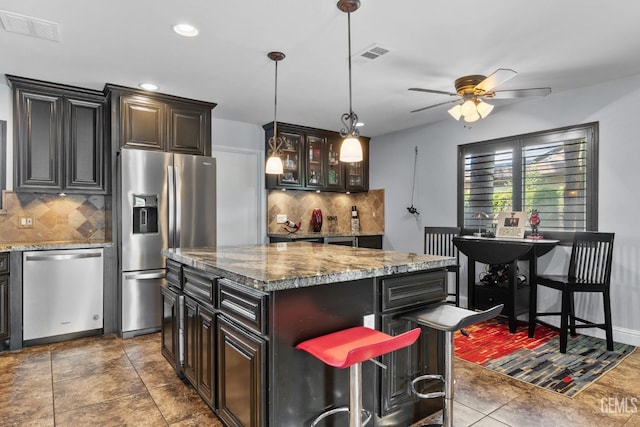 kitchen featuring ceiling fan, appliances with stainless steel finishes, a center island, backsplash, and visible vents