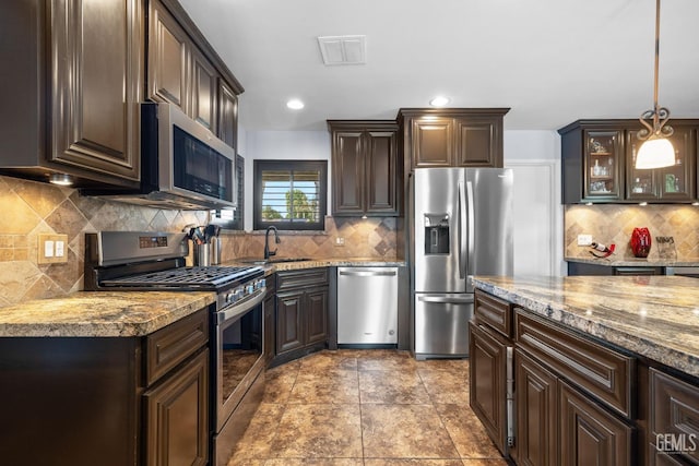 kitchen with dark brown cabinets, appliances with stainless steel finishes, decorative backsplash, and visible vents