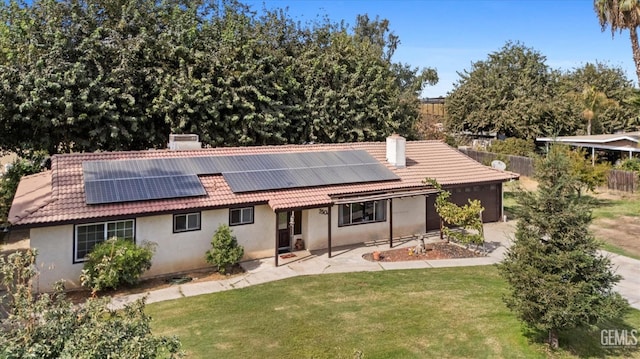 rear view of property featuring solar panels, a yard, and a patio area