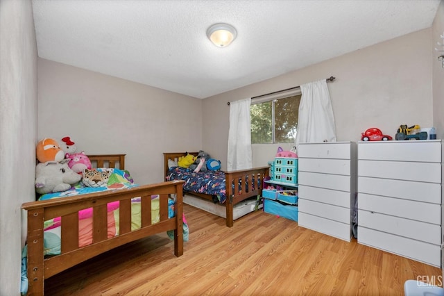 bedroom with light hardwood / wood-style floors and a textured ceiling