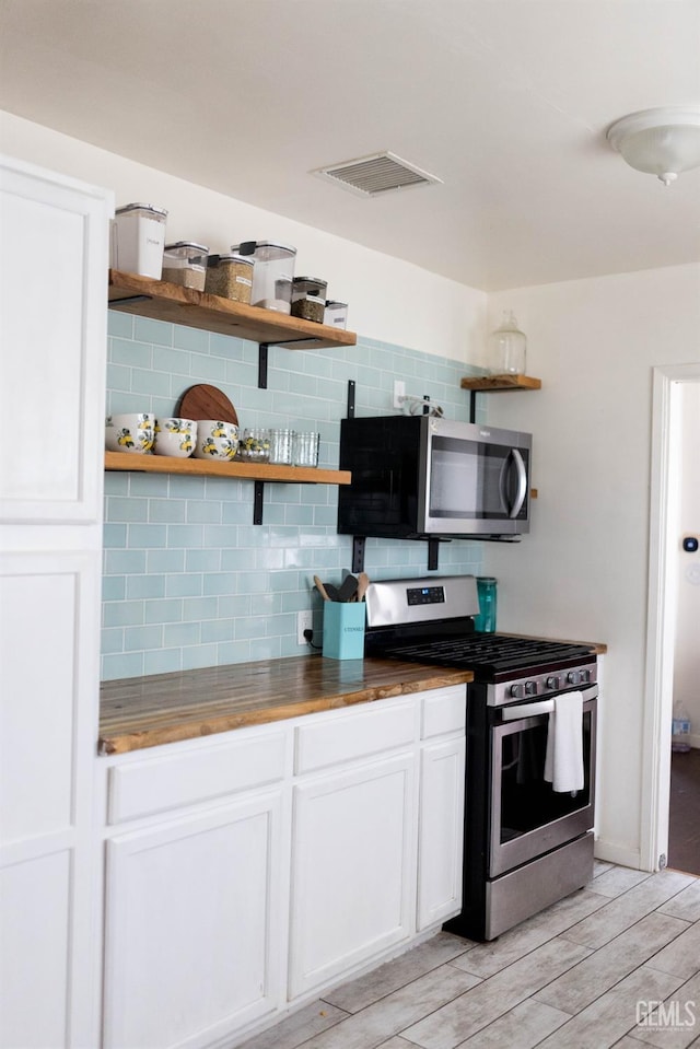 kitchen with appliances with stainless steel finishes, visible vents, wood counters, and open shelves