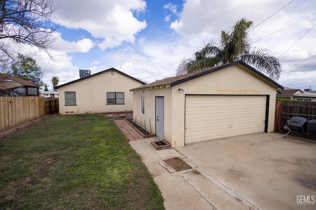 exterior space with an outbuilding, a yard, stucco siding, fence, and a garage