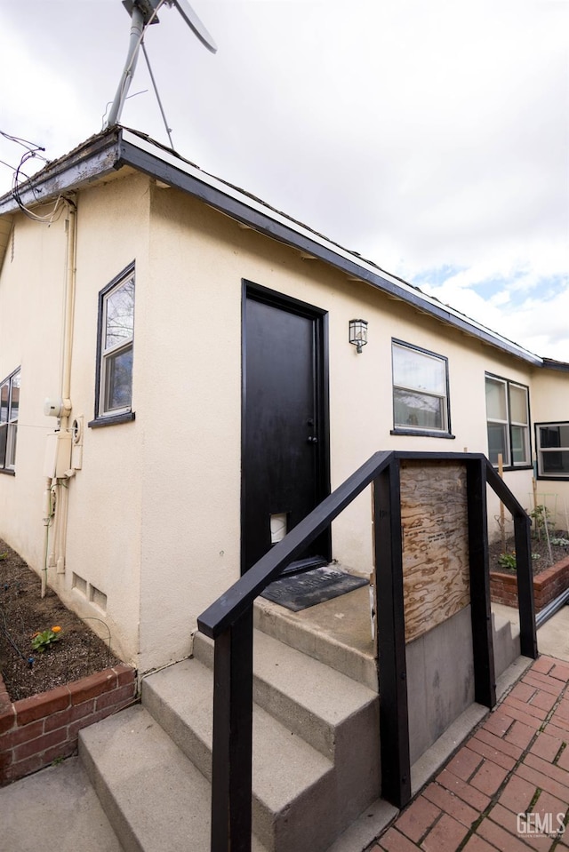 view of exterior entry featuring crawl space and stucco siding