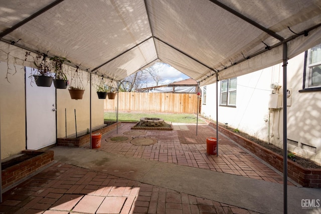 view of patio / terrace with entry steps, glass enclosure, fence, and a fire pit