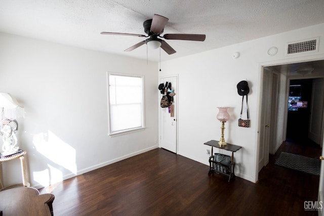 interior space featuring baseboards, visible vents, a ceiling fan, wood finished floors, and a textured ceiling