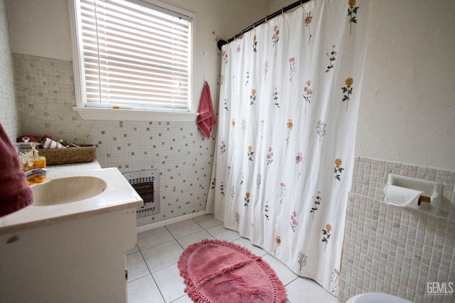 full bath with a wainscoted wall, heating unit, tile patterned flooring, vanity, and tile walls