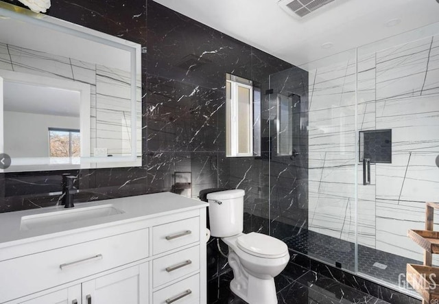 full bath featuring visible vents, toilet, marble finish floor, vanity, and tile walls