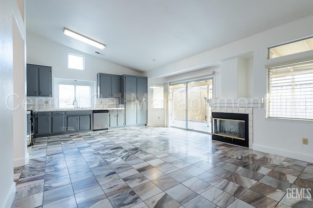 unfurnished living room featuring sink, lofted ceiling, and a tiled fireplace