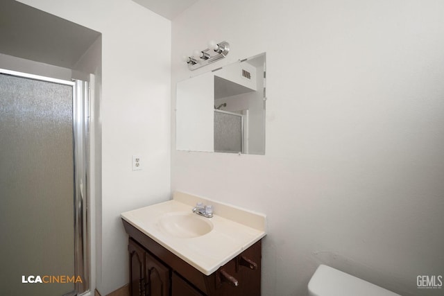 bathroom featuring vanity, a shower with shower door, and toilet