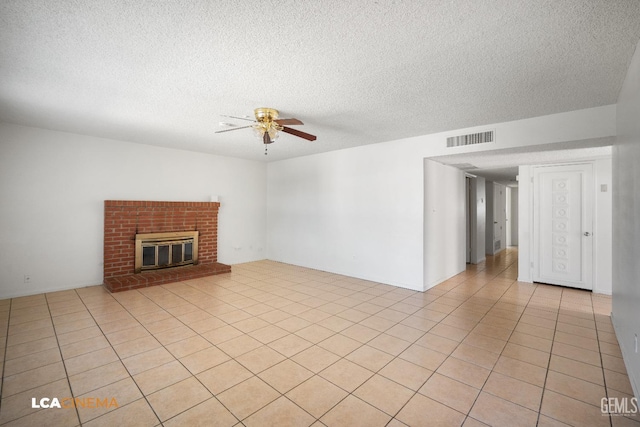 unfurnished living room featuring ceiling fan, light tile patterned floors, a textured ceiling, and a fireplace