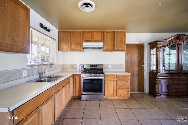 kitchen with sink, stainless steel gas range oven, and light tile patterned flooring