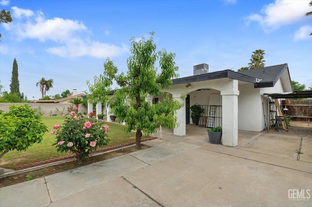 exterior space with fence, a front lawn, central AC unit, and stucco siding